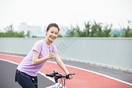 低碳出行青年女性户外公园里骑行背景