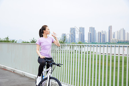 青年女性户外公园骑行休息喝水图片