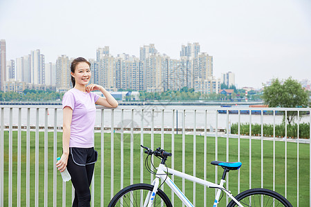 低碳出行青年女性户外公园里骑行背景