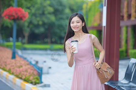 等待公交车的青年女性手捧咖啡杯高清图片