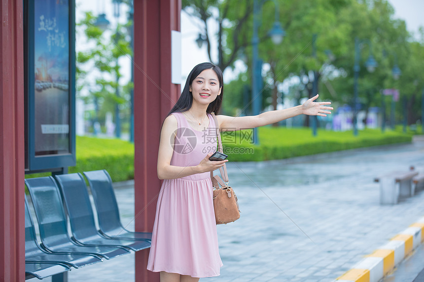 在公交车站台挥手打车的青年女性图片