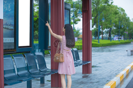 看公交站台指示牌的女性图片