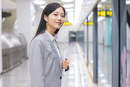 运行的地铁商务女性在地铁站内看书等待背景