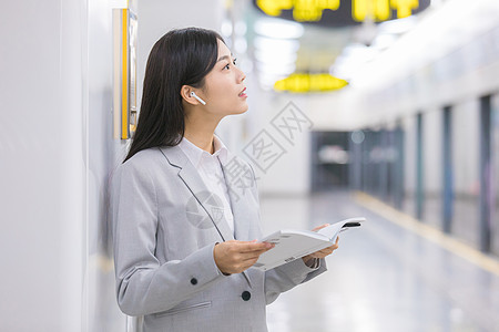 地铁看书商务女性在地铁站内看书等待背景