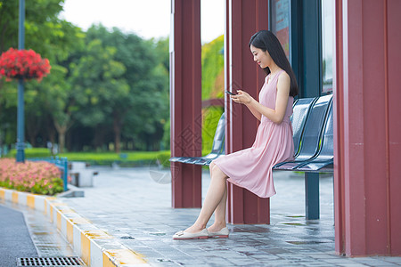 坐在公交站台玩手机的女性图片