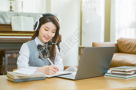 大学生上网戴耳机的女学生上网课做笔记背景
