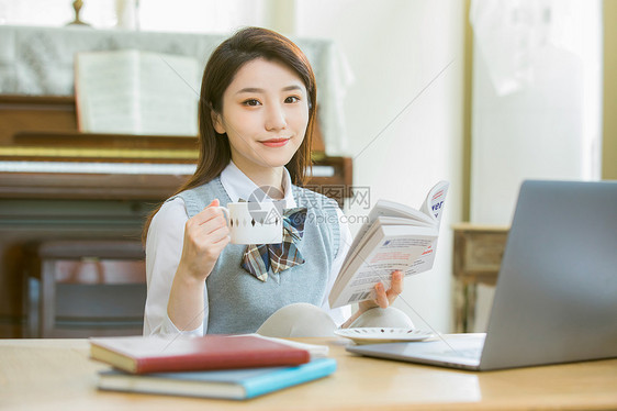 在客厅内喝咖啡看书的女大学生图片