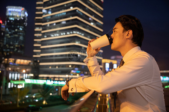 夜晚都市天桥上的商务男性喝咖啡图片