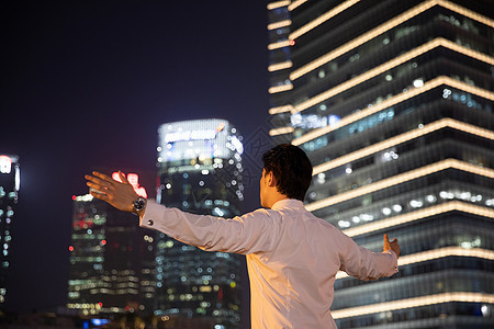 夜晚天桥上的都市商务男性张开双臂背影背景图片