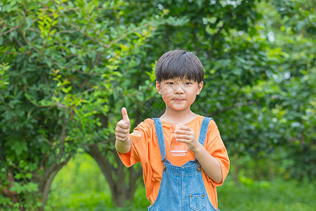 树林前男孩拿着水杯喝水图片