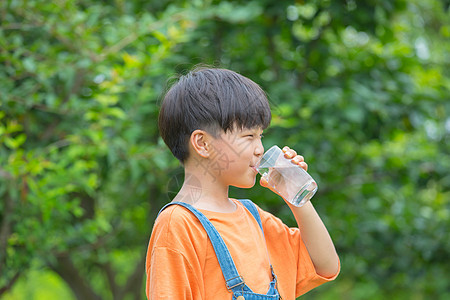 树林前男孩拿着水杯喝水图片