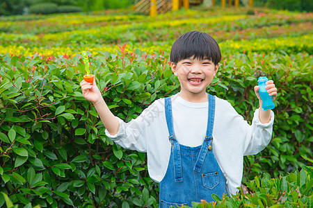 男孩在植物从中吹泡泡图片