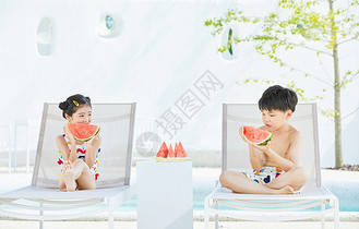 夏日小男孩和小女孩坐在躺椅上开心吃西瓜图片