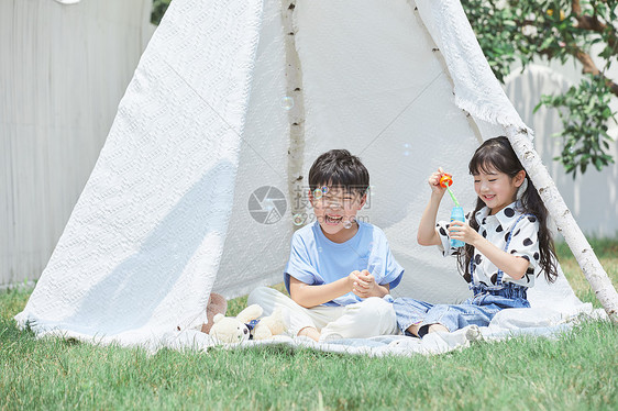 小男孩和小女孩在帐篷里吹泡泡图片