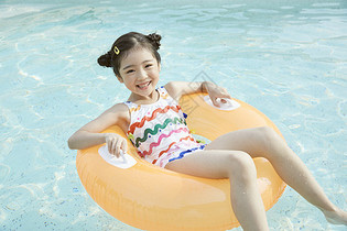 小女孩躺在泳池里的游泳圈上图片