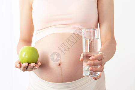孕期营养孕妇手拿苹果和白开水背景