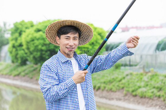 农夫乡间河岸钓鱼拿鱼钩图片