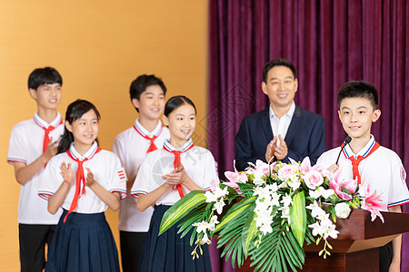 颁奖台上人物在学校礼堂接受表彰的同学们背景