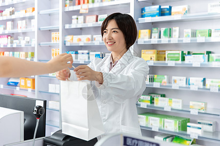药品加工药剂师打包好药品双手递给顾客背景