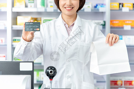 药剂师拿着打包好的药品和信用卡图片