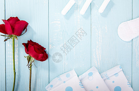 桌面上的鲜花蓝色桌面上的女性卫生用品背景