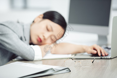 商务女性疲倦趴在桌子上睡觉图片