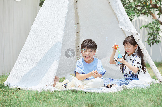 小男孩和小女孩在帐篷里吹泡泡图片