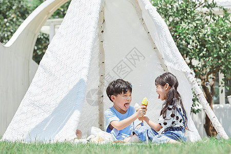 小男孩和小女孩坐在草坪上吃冰淇淋图片