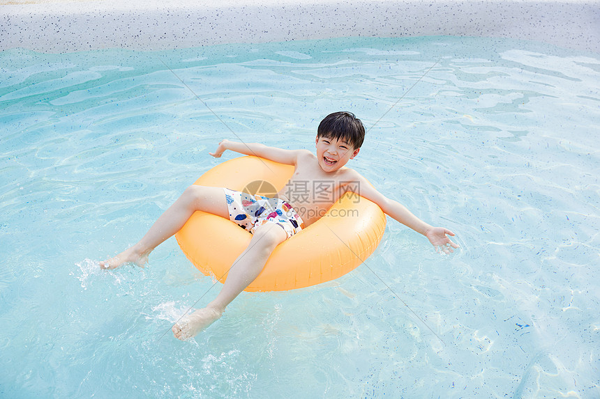 小男孩躺在游泳圈里开心玩水图片
