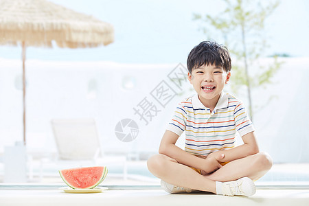 小男孩坐在西瓜旁图片