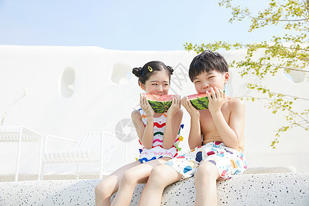 小男孩和小女孩坐在泳池边开心吃西瓜图片