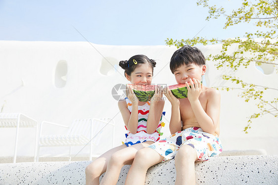 小男孩和小女孩坐在泳池边开心吃西瓜图片