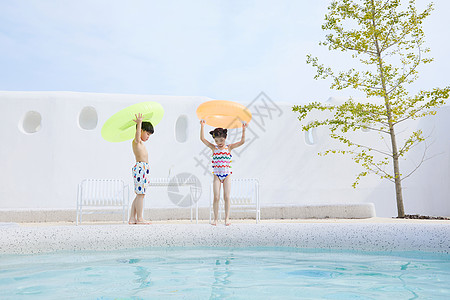 小男孩拿着泳圈小男孩和小女孩拿着泳圈在泳池边行走背景