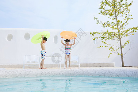 小男孩和小女孩拿着泳圈在泳池边行走图片