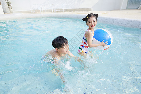 小男孩和小女孩在泳池玩球图片