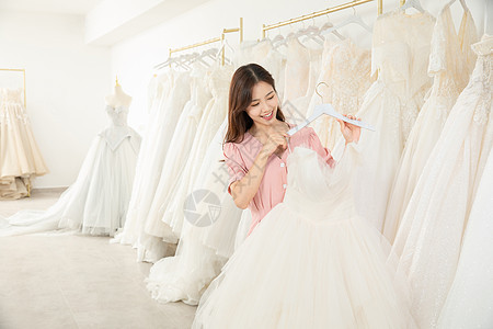 在婚纱店精心挑选婚纱的女孩图片