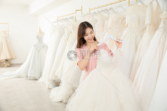 在婚纱店精心挑选婚纱的女孩图片
