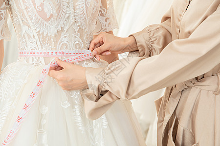 使用皮尺测量婚纱尺寸的设计师特写图片