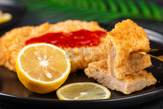 餐盘里的柠檬和涂上番茄酱的鸡排图片