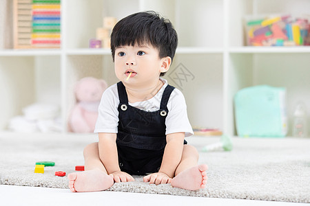 玩耍的小孩子可爱幼儿宝宝坐地毯上吃糖果背景