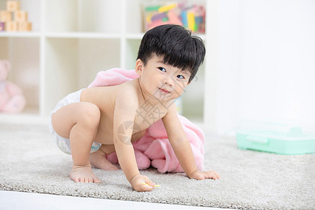 可爱宝宝裹着浴巾在地毯嬉戏高清图片