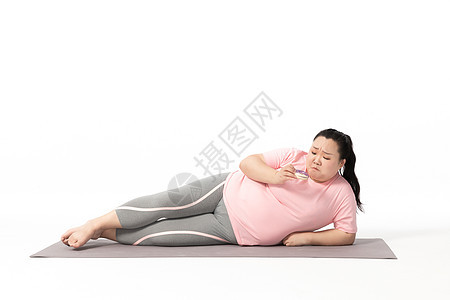 胖女生躺在瑜伽垫上吃甜甜圈图片