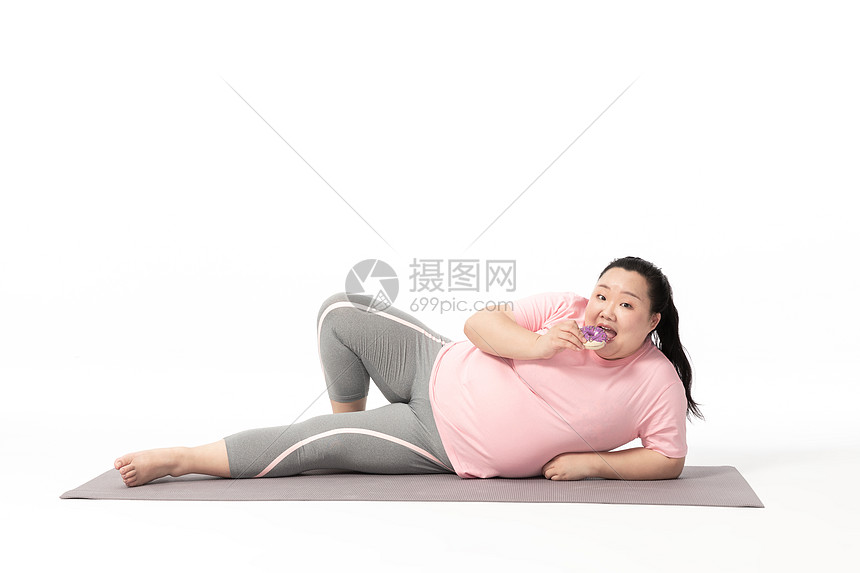 胖女生躺在瑜伽垫上吃甜甜圈图片