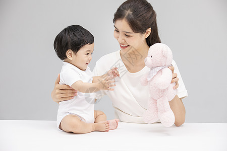婴儿与妈妈年轻妈妈用毛绒玩具逗宝宝开心背景