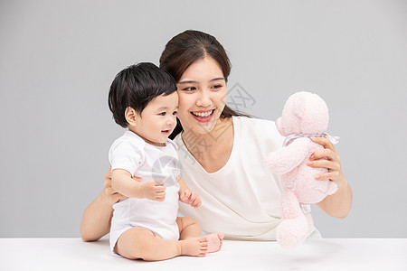 年轻妈妈用毛绒玩具逗宝宝开心图片