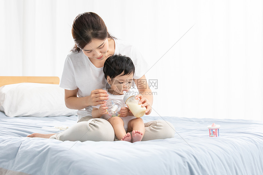 年轻妈妈用奶瓶辅助宝宝喝奶图片