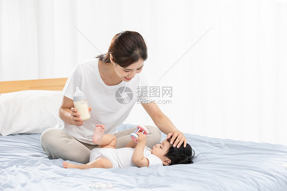 年轻妈妈用奶瓶辅助宝宝喝奶图片