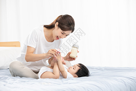 宝宝泡泡浴年轻妈妈用奶瓶辅助宝宝喝奶背景