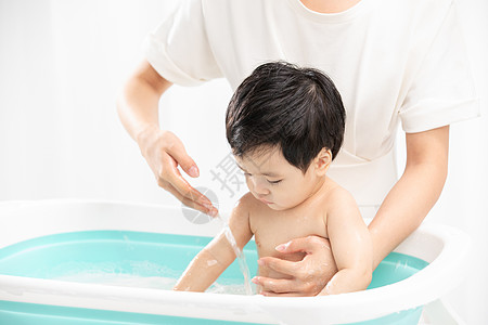 妈妈给宝宝洗泡泡浴年轻妈妈给孩子洗澡背景