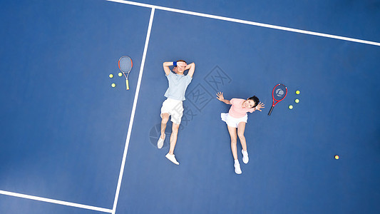 躺在网球场地上休息的青年情侣图片